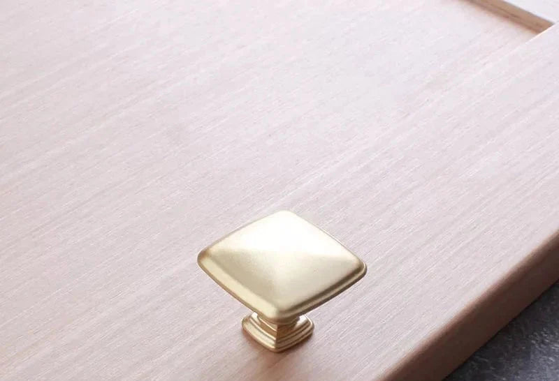 Bouton de meuble carré en or brossé sur fond blanc
