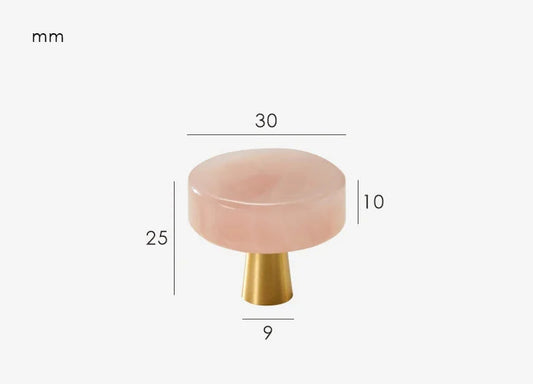 Vue rapprochée d'un bouton de meuble marbre rose et laiton