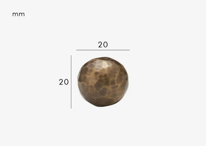 Gros plan sur la texture martelée du bouton en bronze