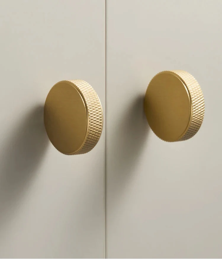 Vue latérale d'un bouton de meuble or brossé avec pierre blanche