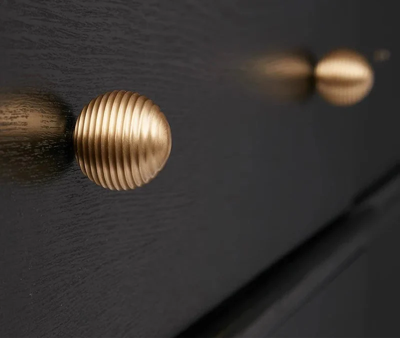 Gros plan sur la texture nervurée du bouton de meuble doré