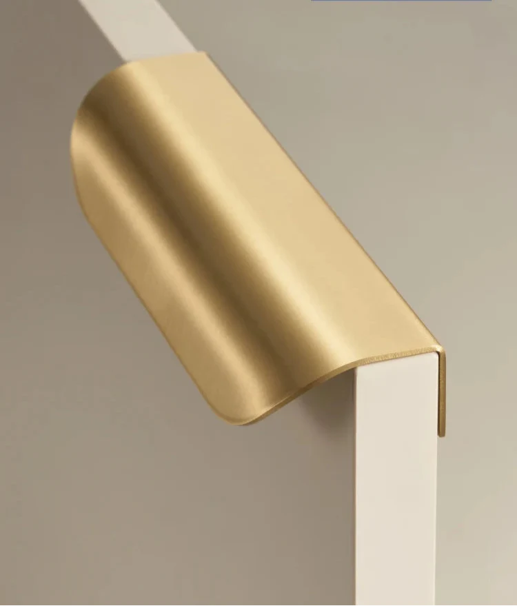 Poignée de meuble en laiton doré sur fond blanc