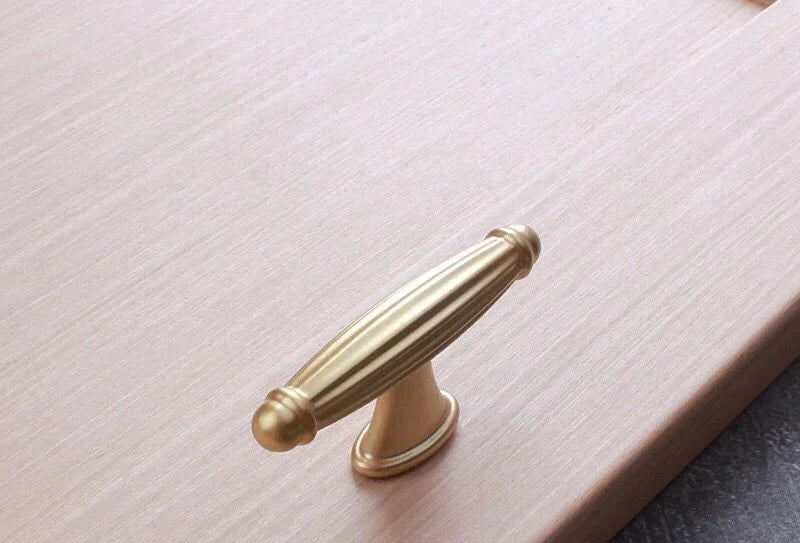 Poignée de meuble vintage en or brossé sur fond blanc