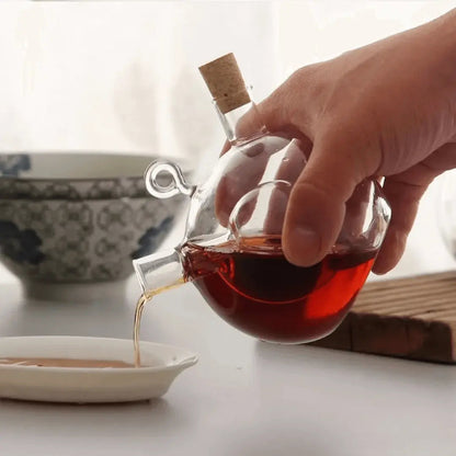 Vue latérale d'une théière en verre tenue à la main