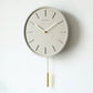 Horloge design avec balancier en métal sur mur blanc