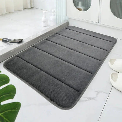 Tapis de bain gris clair sur sol humide, absorbant l'eau