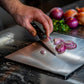 Mains d'un chef coupant un oignon sur une planche